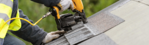 man installing shingles on roof