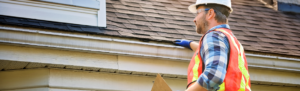man wearing hardhat holding clipboard inspecting roof
