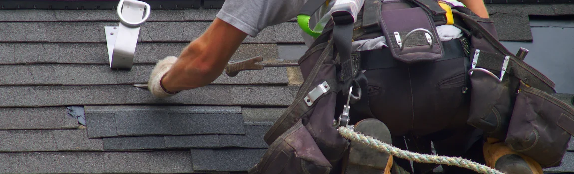 worker fixing shingles on roof